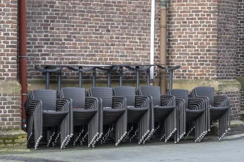 Large quantities of stacked chairs in front of brick wall Stock Photos