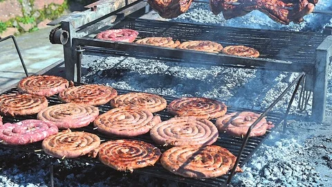 Large quantity of sausage pinwheels that cook at the barbecue Stock Footage 103428049