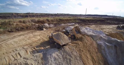 Large quarry dump trucks unload sand into pit aerial view Stock Footage 130383373