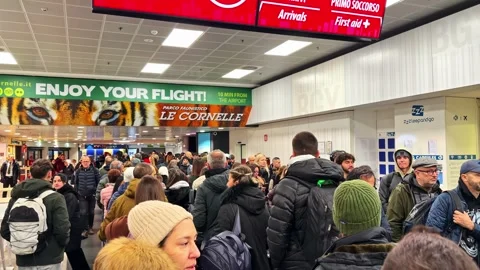 A large queue of travelers stands in line under advertising signs inside a busy Stock Footage 336179159