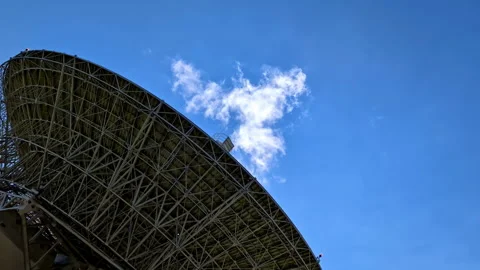 Large radio telescope pointed at clear blue sky with a single cloud Stock Footage 282170981