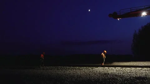 Large rail construction machine illuminated at night with workers on-site Stock Footage 313470099