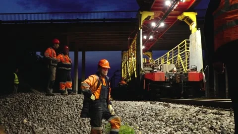 Large rail construction machine illuminated at night with workers on-site Stock Footage 313470101