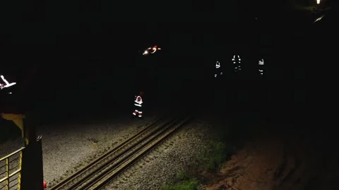 Large rail construction machine illuminated at night with workers on-site Stock Footage 313470119