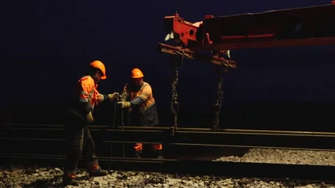 Large rail construction machine illuminated at night with workers on-site Stock Footage 313470123