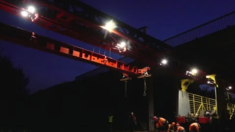 Large rail construction machine illuminated at night with workers on-site Stock Footage 313470142