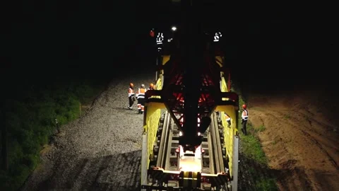 Large rail construction machine illuminated at night with workers on-site Stock Footage 313470163