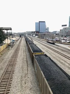 A large railroad yard with a freight train pulling cars of coal through Stock Photos