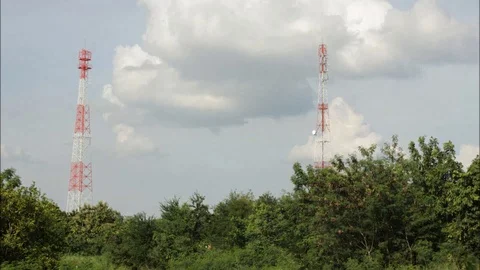Large rain clouds forming between tall red telecommunications towers Stock Footage 96990785