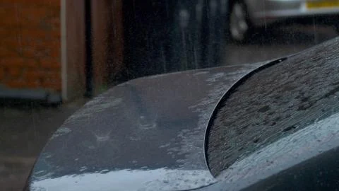 Large rain drops and hailstones strike parked cars during heavy shower in Stock-Fotos