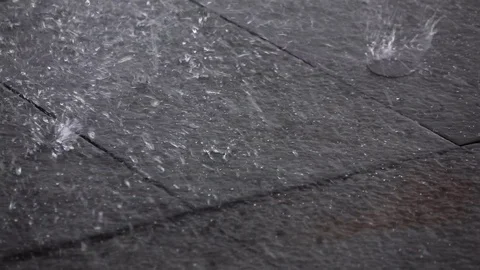 Large rain drops hitting sidewalk slow motion Stock Footage 97570483