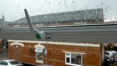 Large rain drops strike open window pane during heavy shower in England Stock-Fotos
