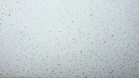 Large rain drops strike a window pane during a summer shower Stock Footage 213067892