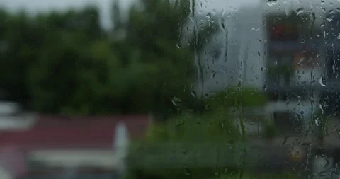 Large rain drops strike a window pane during a summer shower. Water droplets on Stock Footage 270438422