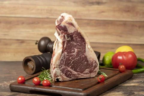 Large raw beef t-bone steak. Veal cowboy steak on rib eye wood presentation b Stock Photos
