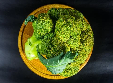 Large raw fresh head of broccoli cabbage on a wooden board, black background, Stock Photos