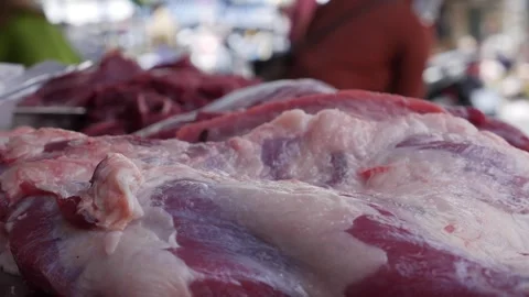 Large raw meat cut resting on a metal tray prepared for sale at a butcher stall 库存影片 333358569