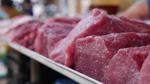Large raw meat cuts arranged on a metal tray at a market stall, thick red pieces Stock Footage 330724795
