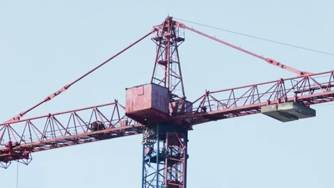 Large red and blue tower crane against clear sky at construction site, heavy Stock Footage 339865993