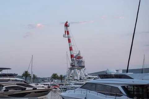 Large red and white shipyard crane stands over luxury yachts Stock Photos