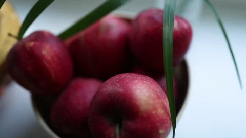 Large red apples next to ripe bananas under green palm leaves Stock Footage 129710105