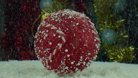 A large red ball on a spinning table is covered with artificial snow, studio Stock Footage 165948290