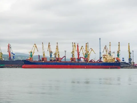 A large red-blue ferry stands in the sea at a pier with coal and a lot of Stock Photos