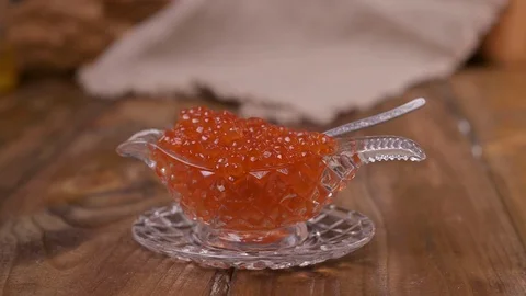Large red caviar in a cup. Studio shot of female hand taking red caviar . Rustic Stock Footage 124339820