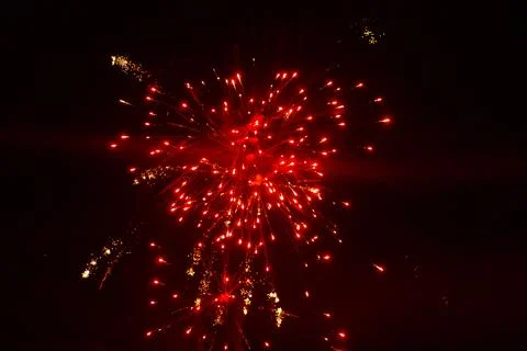 A large red firework explodes, creating glowing trails and golden. Stock Photos