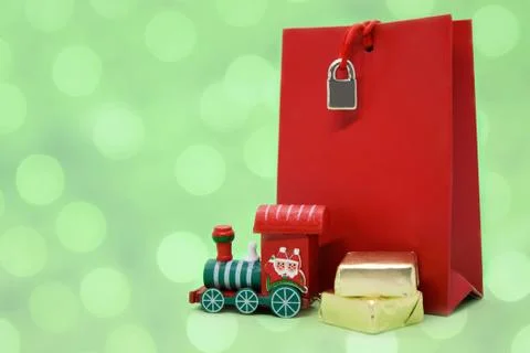 Large red gift bag, small wooden Santa's toy train, and sweaters in gold wrap Stock Photos