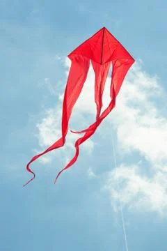 Large red kite flying in a cloudy blue sky Stock Photos