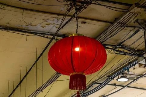 A large red lantern hanging from the ceiling of an old industrial building. Stock Photos