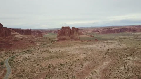 Large red rock formation juts out from flat desert Video stock 167655257