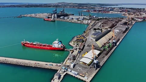 A large red ship is docked at the pier of a busy port 库存影片 339158281