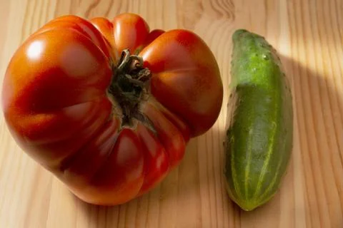 Large red tomato and cucumber on a wooden background Stock Photos