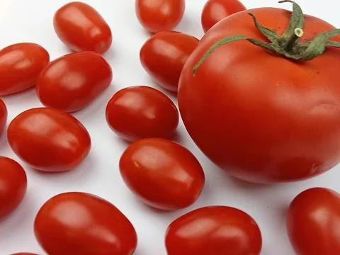 Large red tomato with cherry tomatoes isolated on white Foto stock