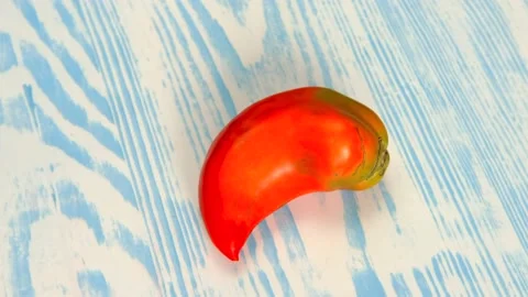 A large red tomato that looks like a pepper is spinning on a wooden Board. Stock Footage 138775365