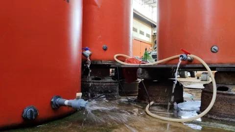 Large red water tanks with connected hoses and visible water flow Stock Footage 304074687