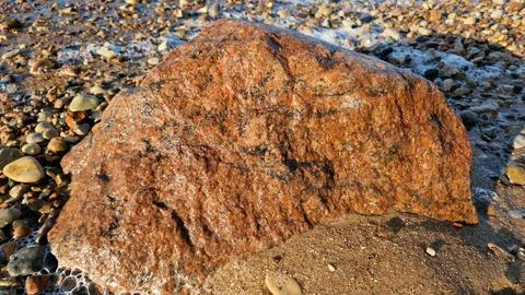 Large Reddish Rock on a Sandy Beach Stock Photos