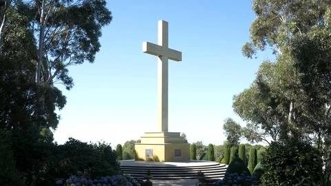 Large remembrance cross in sunlight framed by tall trees either side Stock Footage 102878366