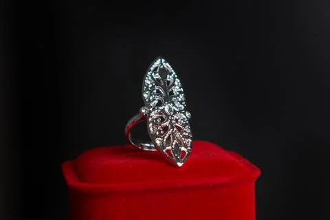 A large ring with small gems on a red box on a dark background. Women's jewel Stock Photos