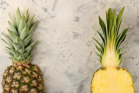Large ripe fruit pineapple. Half a pineapple on a light concrete background. Stock Photos