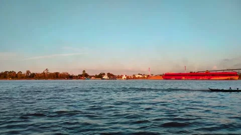 A large river with a coal cargo ship visible in the distance during the day. 4K Stock Footage 287687932