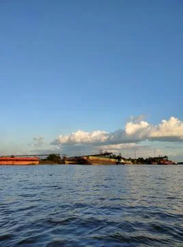 A large river with a coal cargo ship visible in the distance during the day. Stock Photos