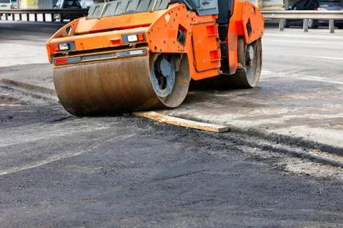 A large road vibratory roller rolls off the highway to lay fresh asphalt on t Foto stock