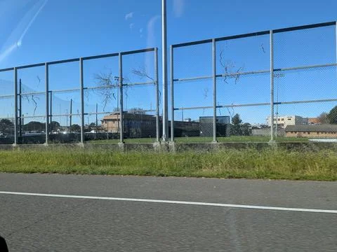 Large roadside fence frames expansive baseball stadium with empty stands Фото