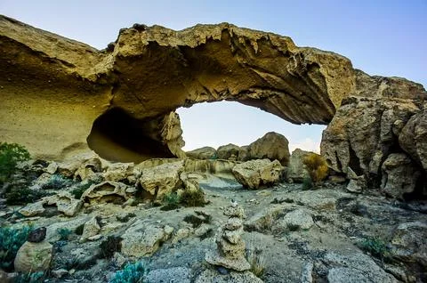 A large rock archway with a small opening in the middle Stock Photos