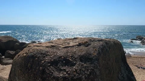 A large rock on the beach with the ocean in the background on a summer day Stock Footage 282255382