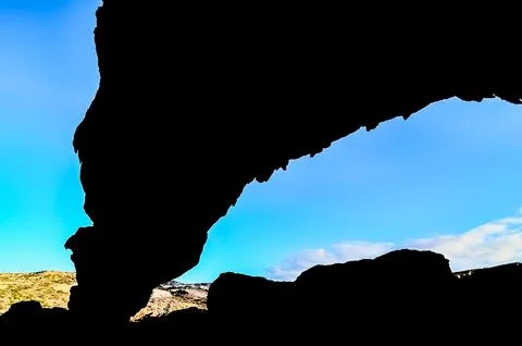 A large rock formation with a dark shadow cast on it Stock Photos