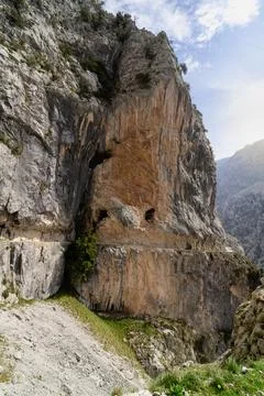 A large rock formation with a small opening in it Stock Photos